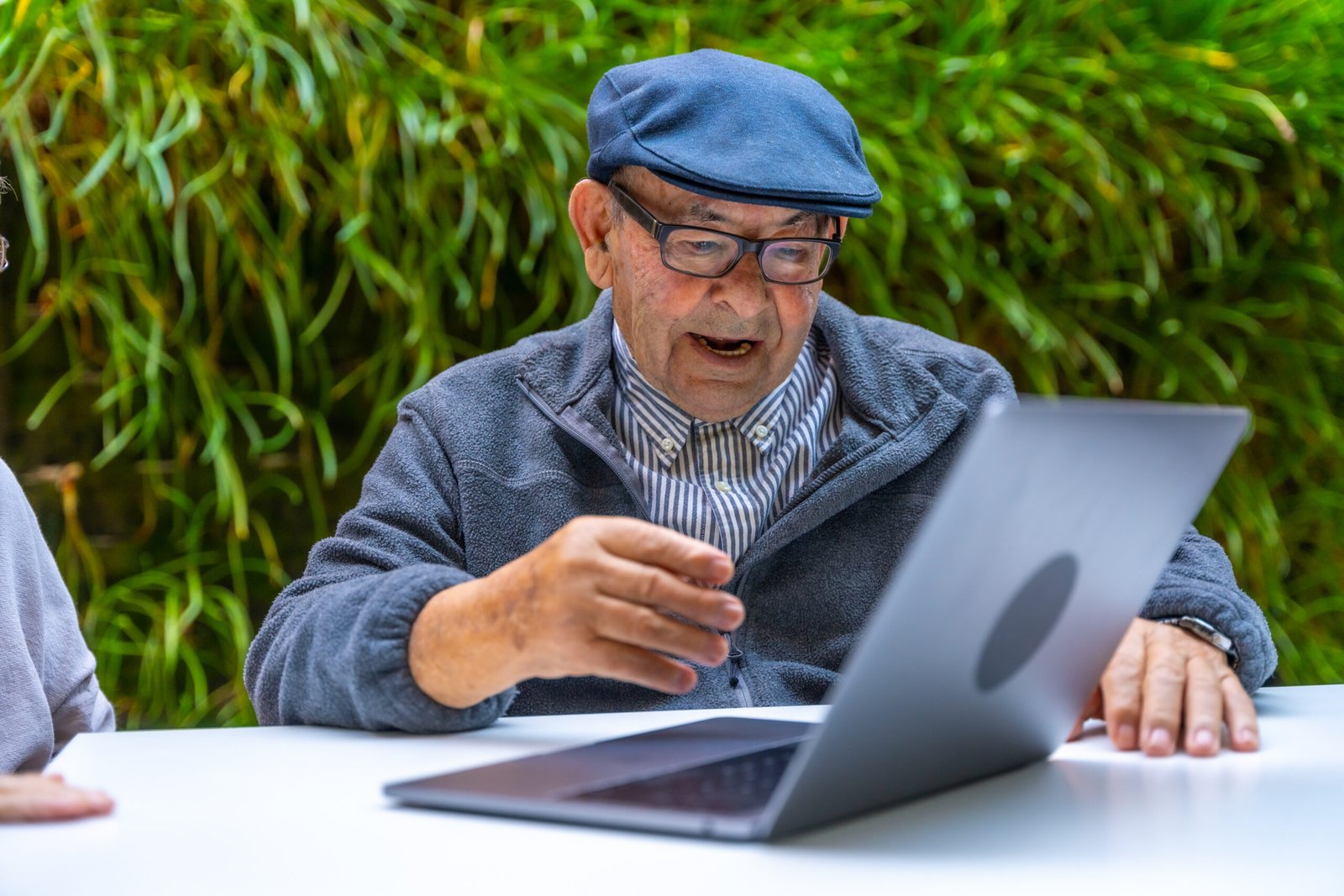Retired man using laptop in a garden learning to use the 501techstack nonprofit website builder